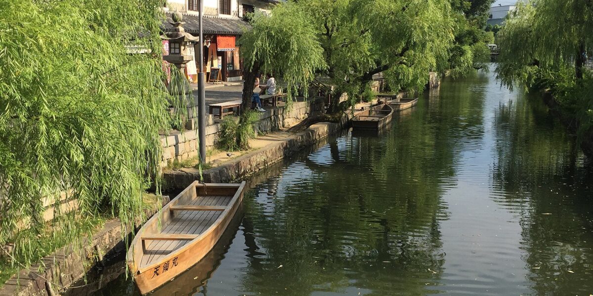 Il canale del quartiere storico Bikan di Kurashiki con salici e magazzini bianchi