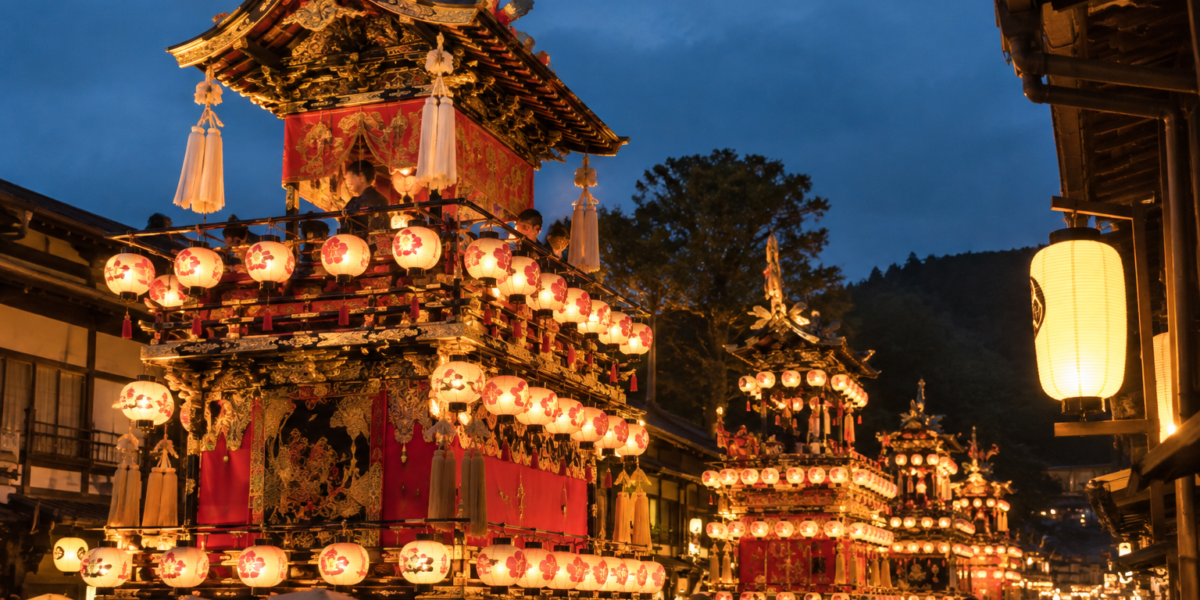 Rappresentazione illustrativa dei carri yatai illuminati di sera durante il festival di Takayama