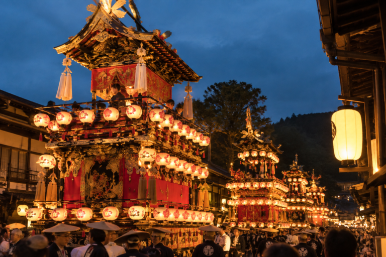 Rappresentazione illustrativa dei carri yatai illuminati di sera durante il festival di Takayama